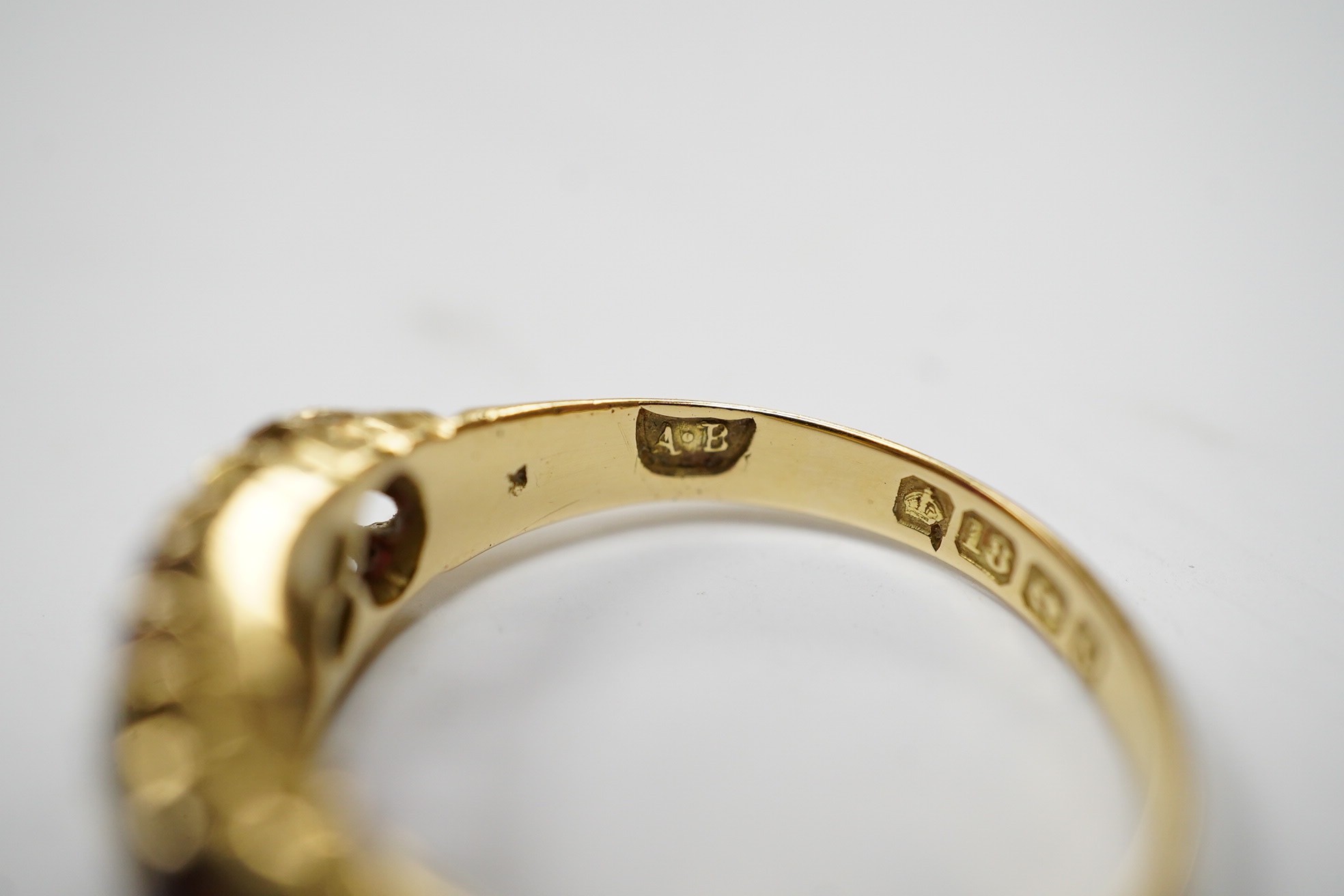 A George V 18ct gold and three stone ruby set half hoop ring, with diamond chip spacers, (one stone is probably a paste replacement), size O, gross weight 3.8 grams. Condition - poor to fair.